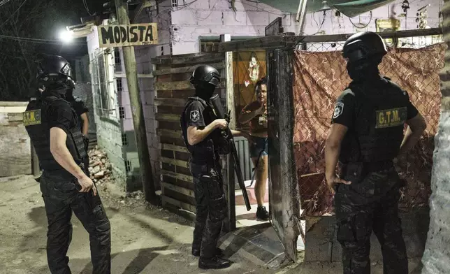 Police officers talk to a woman during an anti-gang operation in the 7 de Septiembre neighborhood of Rosario, Argentina, Tuesday, Nov. 12, 2024. (AP Photo/Rodrigo Abd)