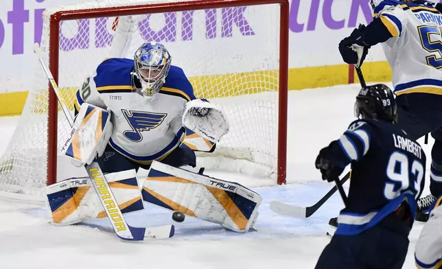 St. Louis Blues goaltender Joel Hofer (30) makes a save on a Winnipeg Jets shot during the first period of their NHL hockey game in Winnipeg, Tuesday December 3, 2024. (Fred Greenslade/The Canadian Press via AP)