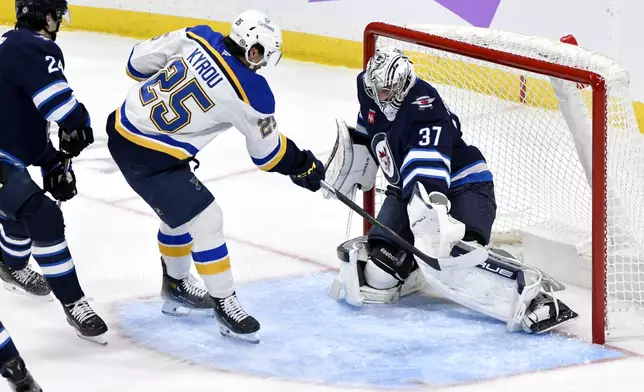 Winnipeg Jets goaltender Connor Hellebuyck (37) makes a save on St. Louis Blues' Jordan Kyrou (25) during the first period of their NHL hockey game in Winnipeg, Tuesday Dec. 3, 2024. (Fred Greenslade/The Canadian Press via AP)