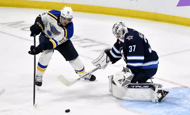 Winnipeg Jets goaltender Connor Hellebuyck (37) makes a save on St. Louis Blues' Radek Faksa (12) during the first period of their NHL hockey game in Winnipeg, Tuesday Dec. 3, 2024. (Fred Greenslade/The Canadian Press via AP)