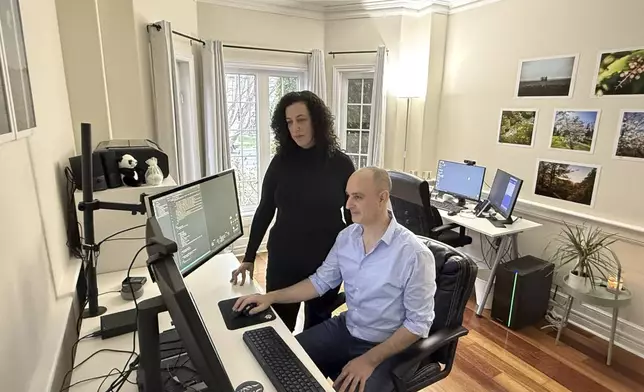 Michal Harel and her husband Avital Epstein show the website they set up to help Israelis navigate a move to Canada in Oakville, Ontario, Canada, Wednesday, Dec. 4, 2024. (AP Photo/Rob Gillies)