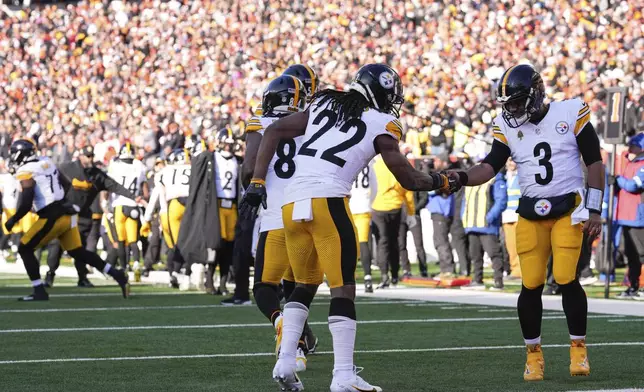 Pittsburgh Steelers running back Najee Harris (22) celebrates with quarterback Russell Wilson, right, after scoring a touchdown during the first half of an NFL football game against the Cincinnati Bengals, Sunday, Dec. 1, 2024, in Cincinnati. (AP Photo/Jeff Dean)