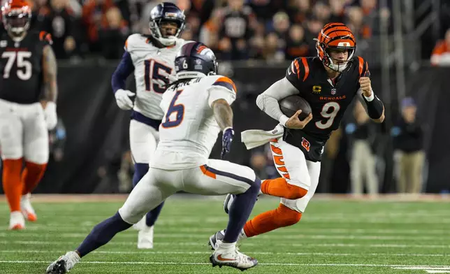 Cincinnati Bengals quarterback Joe Burrow (9) tries to get past Denver Broncos safety P.J. Locke (6) during the second half of an NFL football game in Cincinnati, Saturday, Dec. 28, 2024. (AP Photo/Jeff Dean)