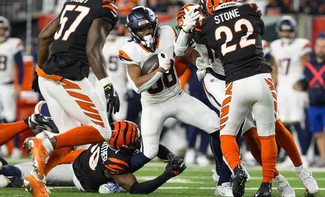 Denver Broncos running back Jaleel McLaughlin (38) is tackled by Cincinnati Bengals linebacker Akeem Davis-Gaither (59) during the second half of an NFL football game in Cincinnati, Saturday, Dec. 28, 2024. (AP Photo/Jeff Dean)