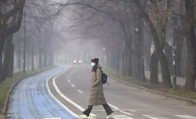 A woman wears a face mask shrouded by pollution haze as smog covers Sarajevo, Bosnia, Thursday, Dec. 19, 2024. (AP Photo/Armin Durgut)