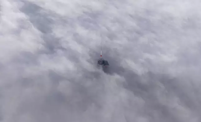 Avaz Twist Tower building, 172 meters high, peaks through a dense layer of fog and smog in Sarajevo, Bosnia, Thursday, Dec. 19, 2024. (AP Photo/Armin Durgut)