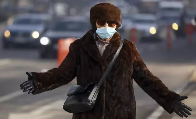 A woman wears a face mask shrouded by pollution haze as smog covers Sarajevo, Bosnia, Thursday, Dec. 19, 2024. (AP Photo/Armin Durgut)