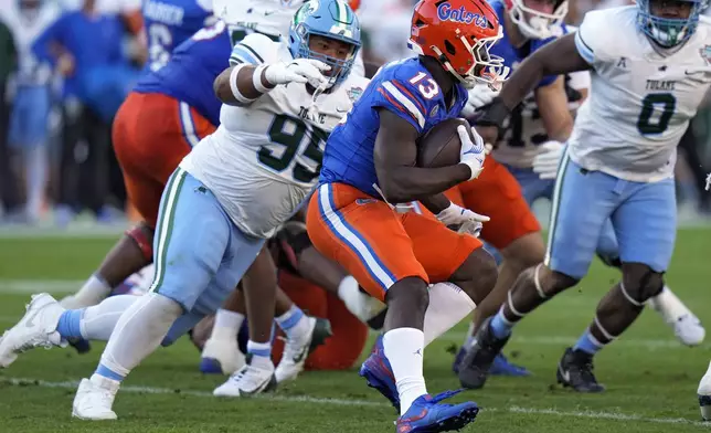 Florida running back Jadan Baugh (13) runs past Tulane nose tackle Adonis Friloux (95) during the first half of the Gasparilla Bowl NCAA college football game Friday, Dec. 20, 2024, in Tampa, Fla. (AP Photo/Chris O'Meara)