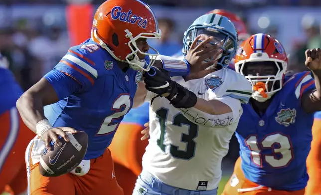 Florida quarterback DJ Lagway (2) stiff arms Tulane linebacker Tyler Grubbs (13) during the first half of the Gasparilla Bowl NCAA college football game Friday, Dec. 20, 2024, in Tampa, Fla. (AP Photo/Chris O'Meara)