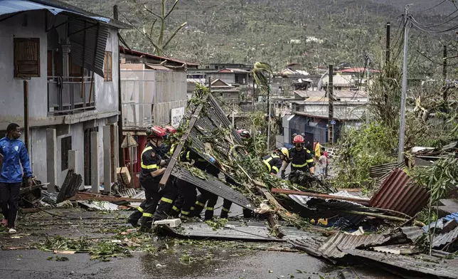 This photo provided on Monday Dec. 16, 2024 by the Civil Security shows rescue workers clearing a street in French territory of Mayotte in the Indian Ocean, after the island was battered by its worst cyclone in nearly a century. (UIISC7/Securite Civile via AP)