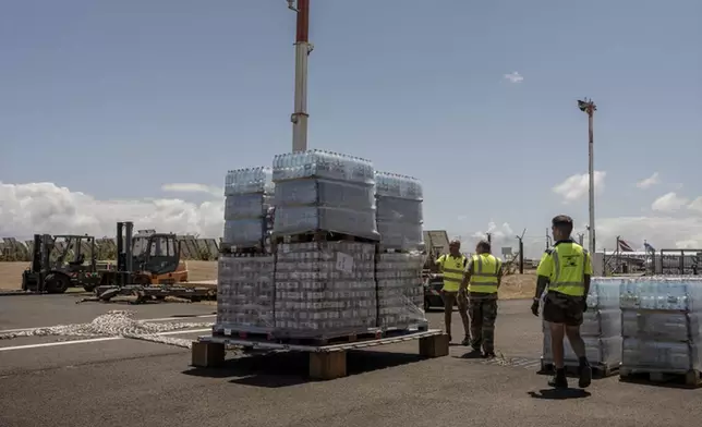 French civil security personnel load pallets of water on a transport plane for Mayotte from Saint Denis on Reunion Island, Tuesday, Dec. 17, 2024. (AP Photo/Adrienne Surprenant)