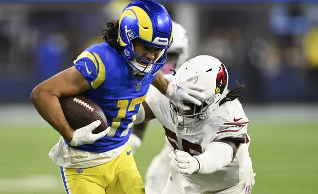 Los Angeles Rams wide receiver Puka Nacua (17) stiff-arms Arizona Cardinals defensive tackle Dante Stills (55) after a reception during the second half of an NFL football game Saturday, Dec. 28, 2024, in Inglewood, Calif. (AP Photo/Alex Gallardo)