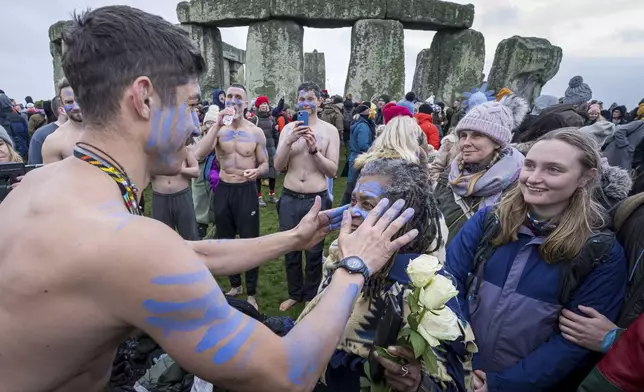 A person's face is daubed with blue paint as they take part in the winter Solstice celebrations at Stonehenge, England, Saturday, Dec. 21, 2024. (AP Photo/Anthony Upton)