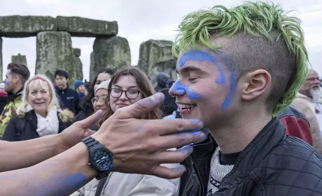 A person's face is daubed with blue paint as they take part in the winter Solstice celebrations at Stonehenge, England, Saturday, Dec. 21, 2024. (AP Photo/Anthony Upton)