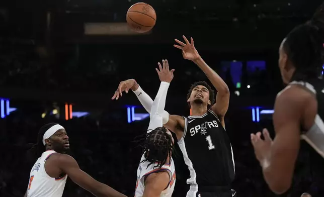 San Antonio Spurs' Victor Wembanyama, second from right, tries to grab a rebound over New York Knicks defenders during the first half of an NBA basketball game, Wednesday, Dec. 25, 2024, in New York. (AP Photo/Seth Wenig)