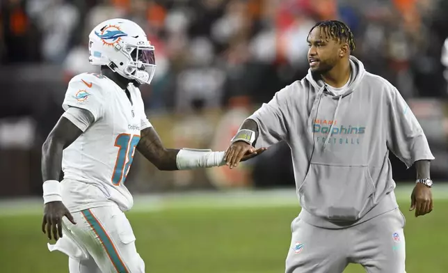 Miami Dolphins quarterback Tua Tagovailoa, right, greets quarterback Tyler Huntley (18) as he comes off the field during the first half of an NFL football game against the Cleveland Browns Sunday, Dec. 29, 2024, in Cleveland. (AP Photo/David Richard)