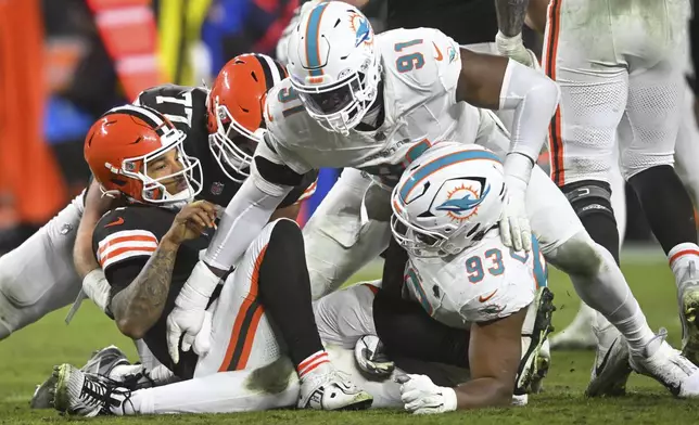 Cleveland Browns quarterback Dorian Thompson-Robinson, left, is tackled by Miami Dolphins linebacker Emmanuel Ogbah (91) and defensive tackle Calais Campbell (93) during the second half of an NFL football game Sunday, Dec. 29, 2024, in Cleveland. (AP Photo/David Richard)