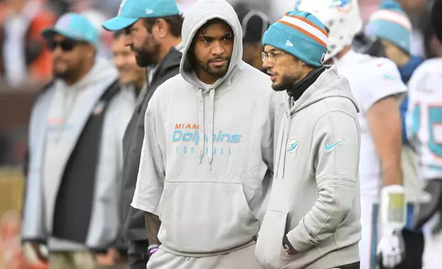 Miami Dolphins quarterback Tua Tagovailoa, left, talks with head coach Mike McDaniel, right, before an NFL football game against the Cleveland Browns Sunday, Dec. 29, 2024, in Cleveland. (AP Photo/David Richard)