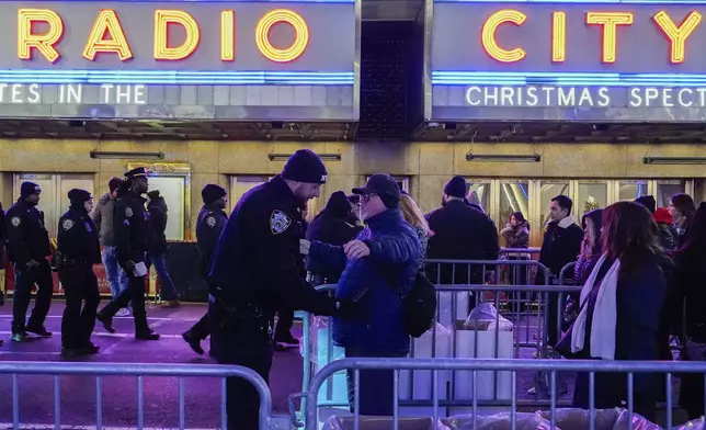 A pedestrian stops for a security check on 51st Street upon arriving at Rockefeller Center for the Christmas tree lighting ceremony, Wednesday, Dec. 4, 2024, in New York. (AP Photo/Julia Nikhinson)