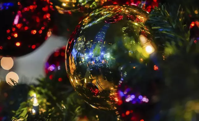The Rockefeller Center Christmas tree reflects in an ornament during the 92nd annual Rockefeller Center Christmas tree lighting ceremony, Wednesday, Dec. 4, 2024, in New York. (AP Photo/Julia Demaree Nikhinson)
