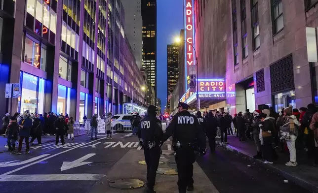New York police officers walk along 51st Street at a security check at Rockefeller Center before the start of the Rockefeller Center tree lighting ceremony, Wednesday, Dec. 4, 2024, in New York. (AP Photo/Julia Nikhinson)
