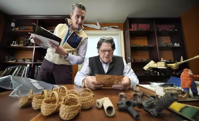 Appraiser Kaja Veilleux, seated, examines a document while associate appraiser Darrin Guitreau takes notes at Thomaston Place Auction Galleries, Tuesday, Nov. 19, 2024, in Thomaston, Maine. (AP Photo/Robert F. Bukaty)