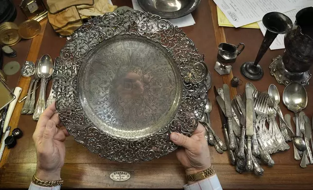 Appraiser Kaja Veilleux looks through a collection of silver items at Thomaston Place Auction Galleries, Tuesday, Nov. 19, 2024, in Thomaston, Maine. (AP Photo/Robert F. Bukaty)