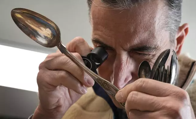 Associate appraiser Darrin Guitreau takes a close look at an inscription on the back of a silver spoon at Thomaston Place Auction Galleries, Tuesday, Nov. 19, 2024, in Thomaston, Maine. (AP Photo/Robert F. Bukaty)