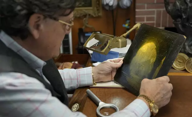 A small oil painting is examined by appraiser Kaja Veilleux for a client at Thomaston Place Auction Galleries, Tuesday, Nov. 19, 2024, in Thomaston, Maine. (AP Photo/Robert F. Bukaty)