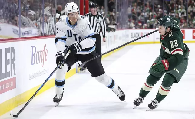 Utah Hockey Club center Nick Bjugstad, left, skates with the puck as Minnesota Wild center Marco Rossi (23) defends during the second period of an NHL hockey game Friday, Dec. 20, 2024, in St. Paul, Minn. (AP Photo/Matt Krohn)