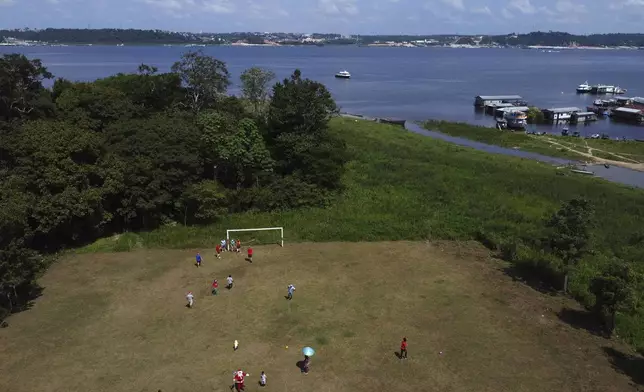 Jorge Barroso, dressed as Santa Claus, joins young residents in a pick up soccer game after arriving on a boat to distribute Christmas gifts to the children, in Iranduba, Brazil, Saturday, Dec. 21, 2024. (AP Photo/Edmar Barros)