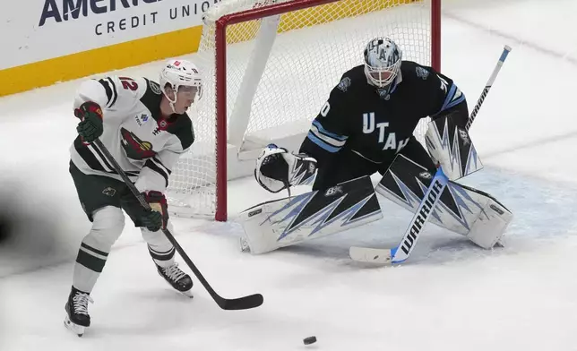 Utah Hockey Club goaltender Karel Vejmelka, right, defends against Minnesota Wild left wing Matt Boldy (12) during the first period of an NHL hockey game Tuesday, Dec. 10, 2024, in Salt Lake City. (AP Photo/Rick Bowmer)