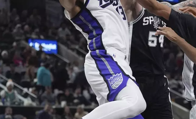 Sacramento Kings forward Keegan Murray (13) grabs a rebound over San Antonio Spurs forward Sandro Mamukelashvili (54) during the second half of an NBA basketball game in San Antonio, Friday, Dec. 6, 2024. (AP Photo/Eric Gay)