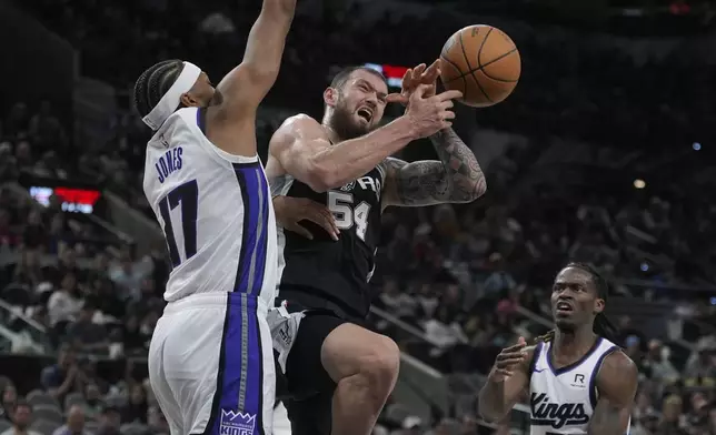 San Antonio Spurs forward Sandro Mamukelashvili (54) is fouled by Sacramento Kings center Isaac Jones (17) as he drives to the basket during the second half of an NBA basketball game in San Antonio, Friday, Dec. 6, 2024. (AP Photo/Eric Gay)