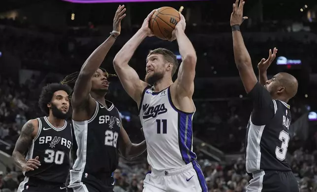 Sacramento Kings forward Domantas Sabonis (11) drives to the basket against San Antonio Spurs center Charles Bassey (28) during the first half of an NBA basketball game in San Antonio, Friday, Dec. 6, 2024. (AP Photo/Eric Gay)