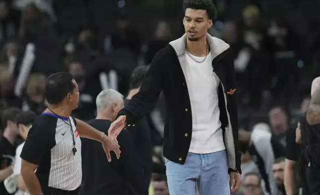 San Antonio Spurs center Victor Wembanyama, right, talks with referee Bill Kennedy, left, during the second half of an NBA basketball game against the Sacramento Kings in San Antonio, Friday, Dec. 6, 2024. (AP Photo/Eric Gay)