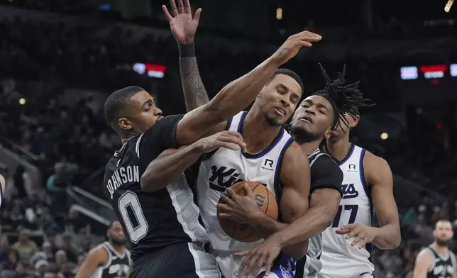 Sacramento Kings forward Keegan Murray, second from left, battles San Antonio Spurs forward Keldon Johnson (0) and guard Stephon Castle, second from right, for a rebound during the second half of an NBA basketball game in San Antonio, Friday, Dec. 6, 2024. (AP Photo/Eric Gay)