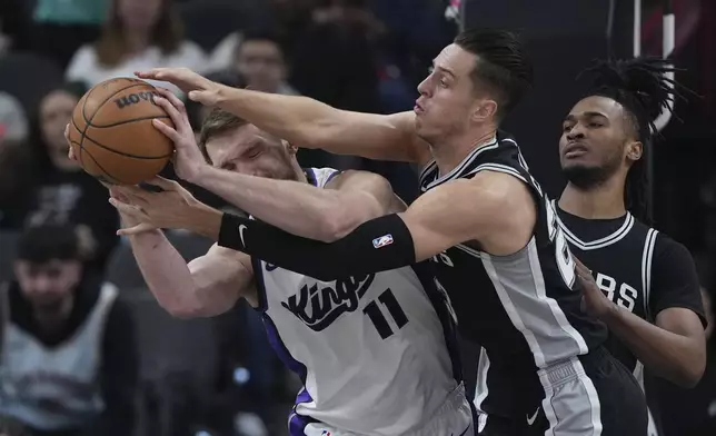 Sacramento Kings forward Domantas Sabonis (11) and San Antonio Spurs forward Zach Collins, center, scramble for a rebound during the first half of an NBA basketball game in San Antonio, Friday, Dec. 6, 2024. (AP Photo/Eric Gay)