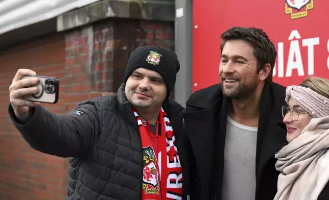 Brandon Sklenar poses for a photo with fans as arrives at SToK Cae Ras, ahead of the English Football League One soccer match between Wrexham and Cambridge United, in Wrexham, Wales, Saturday Dec.14, 2024. (Cody Froggat/PA via AP)