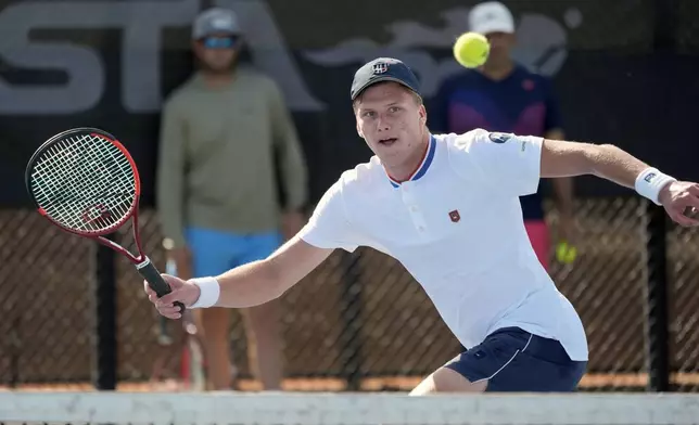 Tennis player Jenson Brooksby practices at the USTA national campus while his coaches Rhyne Williams, back left, and Eric Nunez watch, Tuesday, Dec. 10, 2024, in Orlando, Fla. (AP Photo/John Raoux)