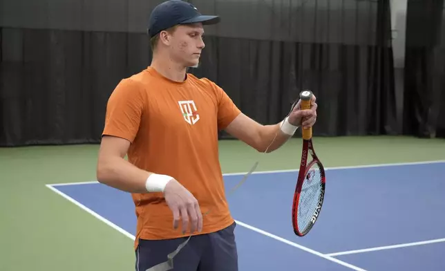 Tennis player Jenson Brooksby fixes tape on his racket grip during a practice session on the indoor courts at the USTA national campus Tuesday, Dec. 10, 2024, in Orlando, Fla. (AP Photo/John Raoux)