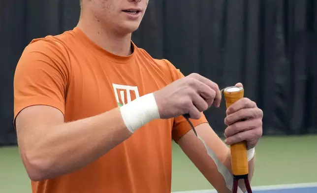 Tennis player Jenson Brooksby fixes tape on his racket grip during a practice session on the indoor courts at the USTA national campus Tuesday, Dec. 10, 2024, in Orlando, Fla. (AP Photo/John Raoux)