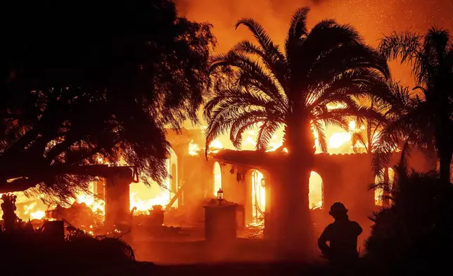 FILE - A firefighter watches as flames from the Mountain Fire consume a home in Camarillo, Calif., Nov. 6, 2024. (AP Photo/Noah Berger, File)