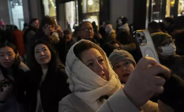 Vlera Islami photographs the flagship Louis Vuitton building on Fifth Avenue, Saturday, Dec. 14, 2024, in New York. (AP Photo/Julia Demaree Nikhinson)