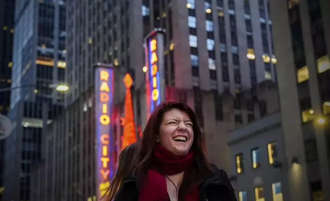 Katarina Cannata laughs while filming a video in front of Radio City Music Hall on Sixth Avenue, Saturday, Dec. 14, 2024, in New York. (AP Photo/Julia Demaree Nikhinson)