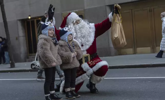 Nora and Rose Caldwell take photos with Santa outside of Rockefeller Center, Friday, Dec. 13, 2024, in New York. (AP Photo/Julia Demaree Nikhinson)