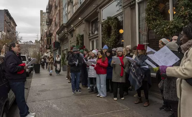 John Herzfeld, left, leads a group of carolers during the West Village Chorale's 50th annual Greenwich Village caroling walk, Sunday, Dec. 15, 2024, in New York. (AP Photo/Julia Demaree Nikhinson)