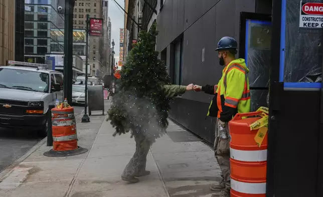 Tommy Liberto, known as Mr. Christmas Tree, fist bumps a construction worker while visiting New York for the tenth year from Bel Air, Md., Wednesday, Dec. 4, 2024. (AP Photo/Julia Demaree Nikhinson)