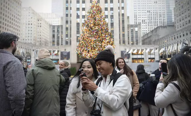 Su and Mo Kyi take a selfie in front of the Rockefeller Center Christmas tree, Friday, Dec. 13, 2024, in New York. (AP Photo/Julia Demaree Nikhinson)