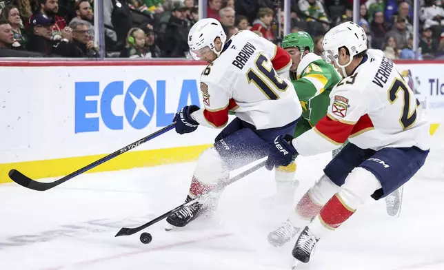 Florida Panthers center Aleksander Barkov, left, and center Carter Verhaeghe (23) defend the puck from Minnesota Wild defenseman Jared Spurgeon during the second period of an NHL hockey game Wednesday, Dec. 18, 2024, in St. Paul, Minn. (AP Photo/Matt Krohn)